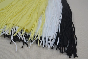 Close-up detail of layered long fringe tassels in yellow, white, and black bandage dress fabric