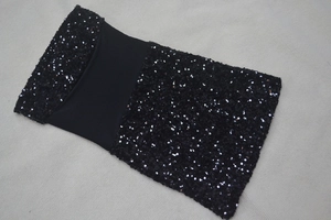 Dettaglio delle paillettes nere lucide cucite sul tessuto elastico di un abito a fascia
