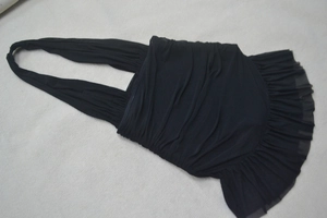 Detail of black halter mesh dress featuring ruched fabric and layered ruffle hemline
