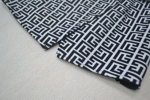 Detail shot of black and white geometric jacquard knit fabric with intricate labyrinth texture