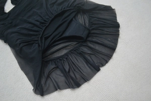 Detail of black mini dress featuring tiered mesh ruffles and built-in safety lining