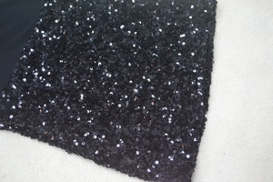 Dettaglio delle paillettes nere fitte sul tessuto dell'abito da cocktail attillato