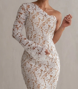 Close-up of white floral lace fabric and asymmetrical one-shoulder sleeve on the dress