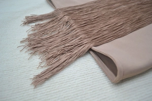 Detailed macro view of dense long fringes on light brown bandage fabric dress