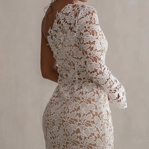 Close-up of elegant white floral lace texture on a single-shoulder evening gown dress