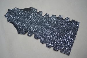 Detail of black mini dress with silver sequins featuring unique scalloped edge and side cutouts