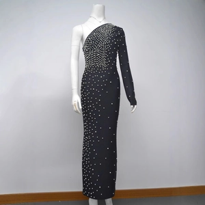 Détail d'une robe noire à une épaule avec des perles blanches parsemées de haut en bas
