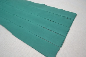 Gros plan sur le tissu vert de la robe bandage montrant la texture et les coutures de qualité