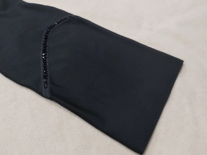 Close-up of black bandage dress showing elegant faceted beadwork and fine stitching details