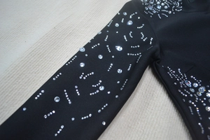 Detail of black bandage dress featuring silver rhinestones in radial patterns on the sleeve