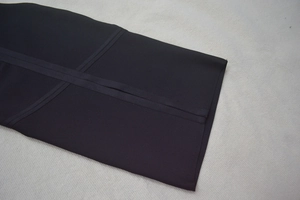 Close-up of black bandage dress featuring premium stitching and cross-strap fabric details