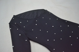 Détail de la robe noire à épaule dénudée avec perles blanches et doublure scintillante