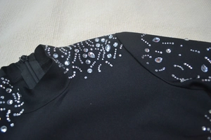 Detail of black high-neck bandage dress showing rhinestones and back zipper