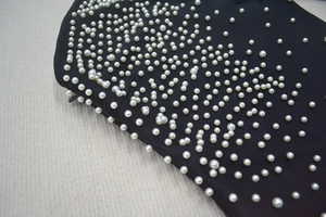 Détail d'une robe bandage noire avec perles cousues main et fermeture éclair latérale invisible