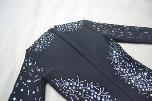 Close-up of luxury rhinestones and beadwork on black long sleeve bandage dress