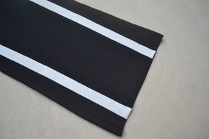 Gros plan détaillé du poignet de la robe noire avec deux bandes blanches contrastantes