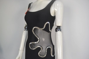 Dettaglio dell'inserto in rete laterale con bordo in strass scintillanti sul vestito nero