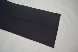 Détail de la fente et des coutures fines sur une robe noire à épaules dénudées