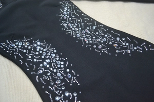 Detailed close-up of sparkling silver rhinestones on a black bandage dress fabric