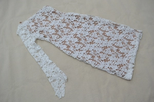 Detail of white floral lace fabric with nude lining for elegant one-shoulder dress