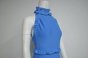 Detail of light blue sleeveless backless knit dress with ruffled hem and halter neck