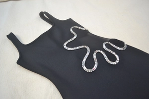 Dettaglio abito bandage nero con ritagli a onde di strass e pannelli laterali in mesh