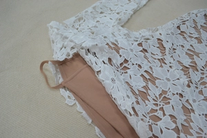 Detail of white floral lace evening dress with thin strap and nude inner lining