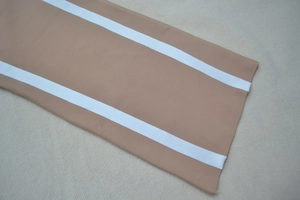 Détail de la manchette de robe kaki avec deux bandes blanches sur tissu texturé