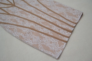 Vue détaillée d'appliqués de dentelle florale blanche sur tulle nude avec lignes brunes