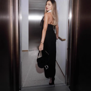 Détail d'une robe noire dos nu avec revers blanc et sac à pendentif métallique en D