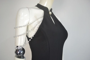 Detail of black halter bandage dress featuring triple-layered pearl shoulder chains