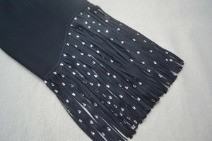 Détail de la robe bandage noire avec de longues franges et des strass argentés brillants