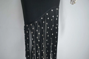 Détail de la robe bandage noire montrant des franges denses ornées de strass brillants