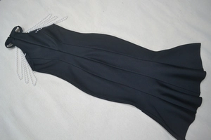Detail view of the black sleeveless bandage dress featuring elegant pearl chain tassels