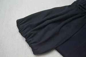Détail du tissu froncé et de la couture sur la robe bandage noire à épaules dénudées