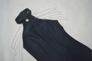 Detail of elegant black halter dress featuring pearl chain shoulders and teardrop cutout