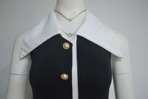 Détail du col blanc élégant et des boutons en perles sur une robe en maille noire