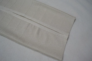 Détail macro du tissu bandage champagne avec de fins reflets métalliques et texture luxe
