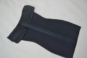 Détail de la robe bandage noire à épaules dénudées montrant la texture et la fermeture