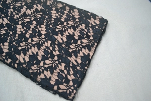 Close-up of black floral lace fabric with nude lining showing intricate hollow patterns