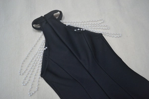 Detail of elegant black bandage dress featuring luxurious pearl chain fringe on shoulders
