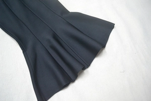 Detail of black bandage dress featuring precise topstitching and elegant ruffled hemline