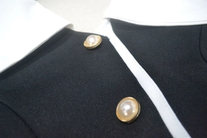Détail d'une élégante robe noire avec col blanc et boutons de perles bordés d'or fin