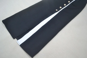 Détail d'une robe noire avec bande blanche contrastée et boutons dorés élégants