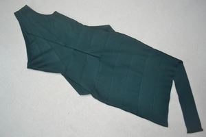 Detail of forest green one-shoulder bandage dress showing ribbed texture and side zipper