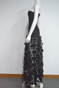 Detail of strapless black party dress featuring 3D floral petals on a mesh skirt