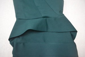 Macro shot of dark green peplum ruffle detail and textured knit fabric on a dress