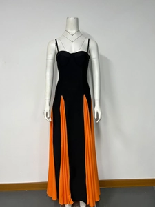 Detail of color-block contrast dress with black bodice and orange pleated maxi skirt