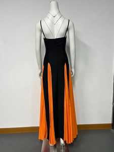 Detail of contrast color pleated dress featuring black bodice and orange chiffon hemline