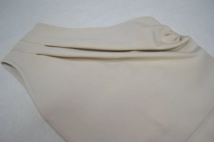 Détails rapprochés de la robe bandage beige montrant les plis superposés et le tricot